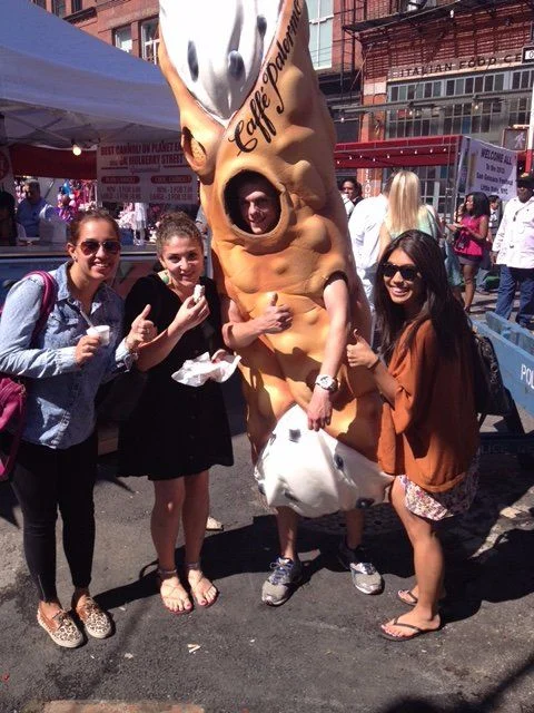 Visitors posing with a giant Caffè Palermo cannoli costume at a street celebration