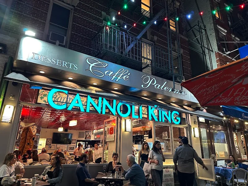 The illuminated Cannoli King sign and café tables on Mulberry Street